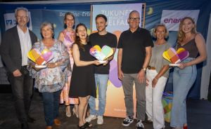 Mehrere Personen freuen sich und halten insgesamt drei Awards in der Hand.